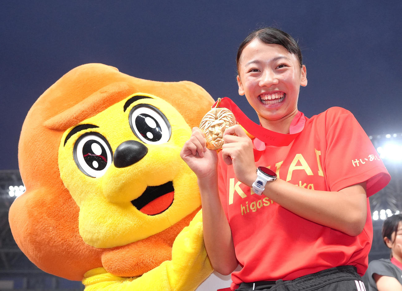 女子800メートル決勝を日本新記録で優勝した久保は日本陸上競技連盟マスコット「アスリオン」の祝福に笑顔を見せる（撮影・足立雅史）