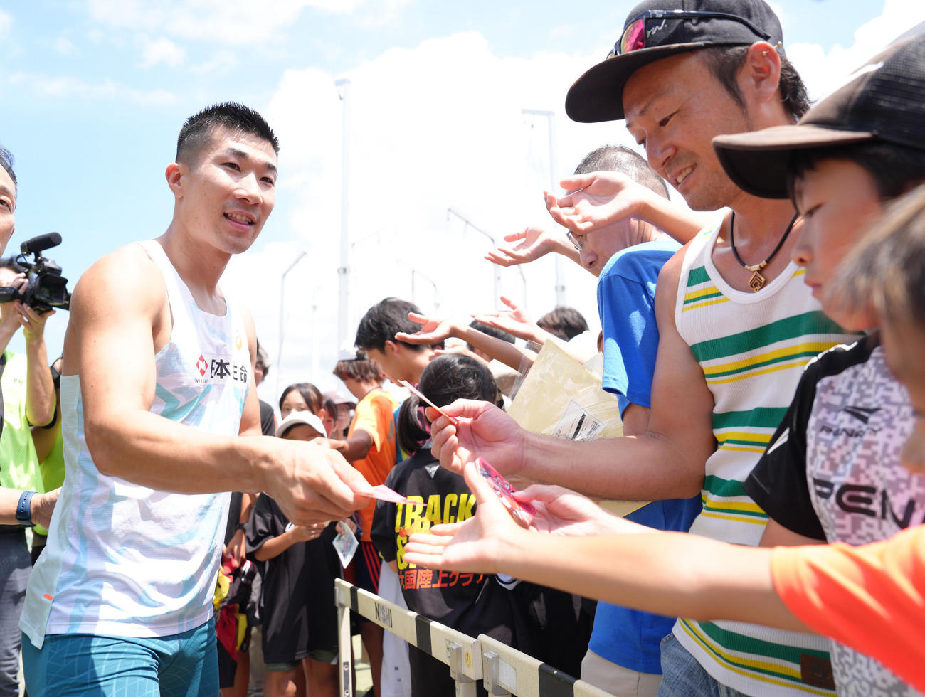 男子100メートル予選で9秒99をマークした桐生はファンにステッカーをプレゼントする（撮影・足立雅史）