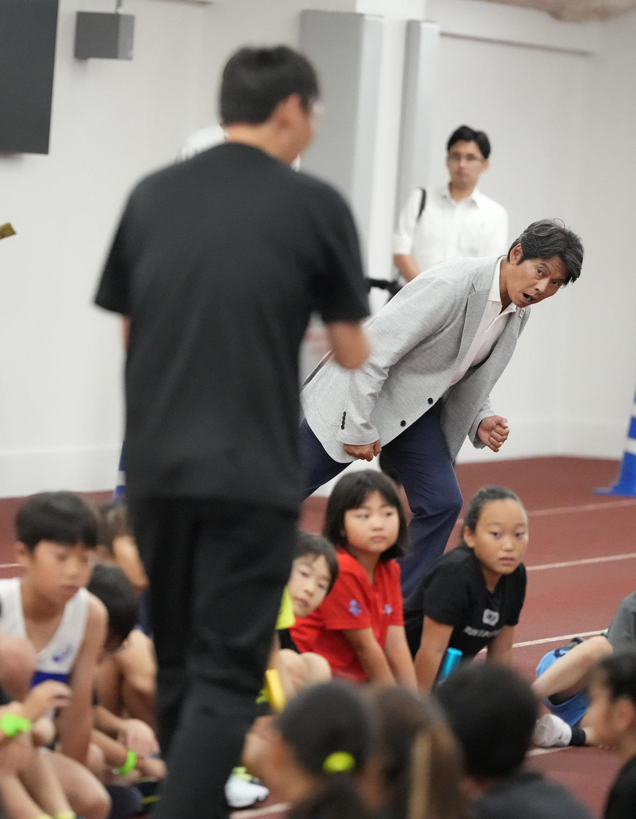 東京2025世界陸上「バトンプロジェクト」特別イベントで子どもたちに授業する北京五輪銀メダリストの高平慎士（左）に合わせスタートのポーズを真似る大会スペシャルアンバサダーの織田裕二（撮影・小沢裕）