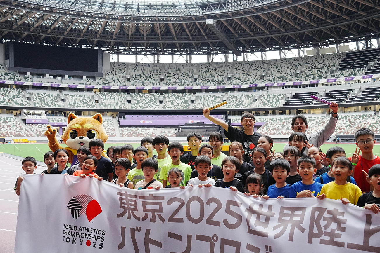 東京2025世界陸上「バトンプロジェクト」特別イベントで参加した子どもたちと記念撮影に臨む公式マスコットのりくワン（後列左）、後列右から大会スペシャルアンバサダーの織田裕二、北京五輪銀メダリストの高平慎士（撮影・小沢裕）