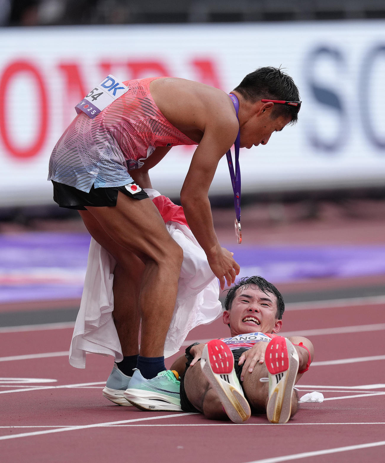 男子35キロ競歩決勝でゴールし疲労困憊（こんぱい）で倒れ込んだ川野（右）に手を差し出す勝木（撮影・足立雅史）