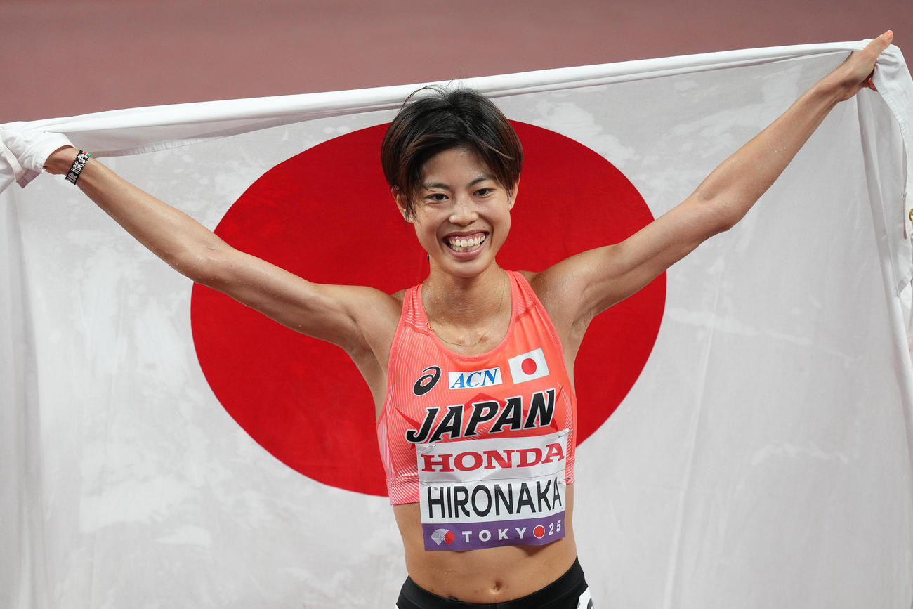 女子1万メートル決勝で6位入賞し笑顔で日の丸を掲げる広中（撮影・足立雅史）