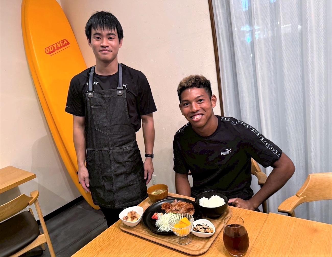 サニブラウン（右）から贈られたエプロンを身につけて写真におさまる専属シェフの植松宏太さん（UDN SPORTS提供）