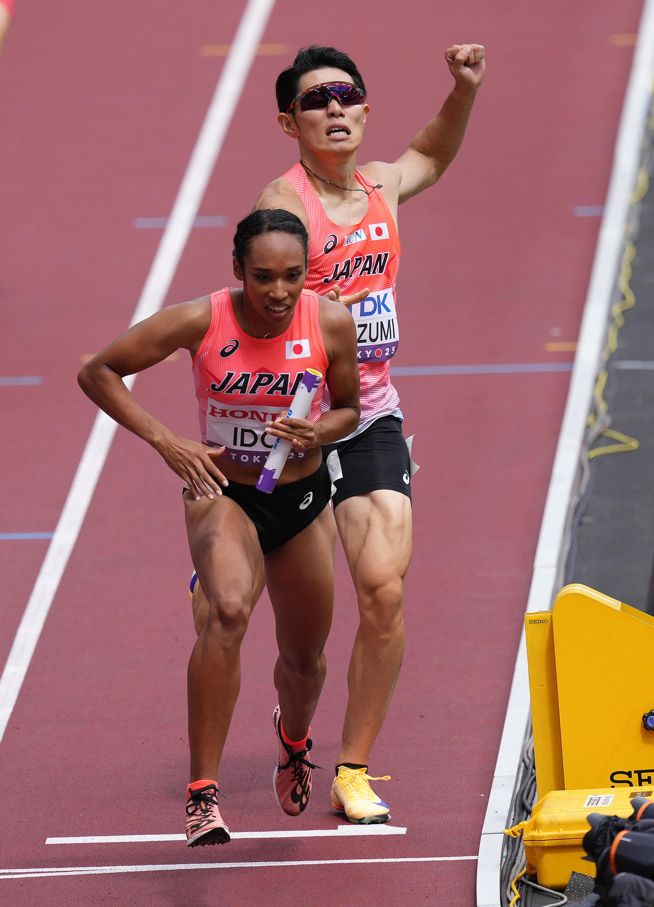 混合1600メートルリレー予選、1走今泉（後方）から2走井戸にバトンが渡る（撮影・足立雅史）