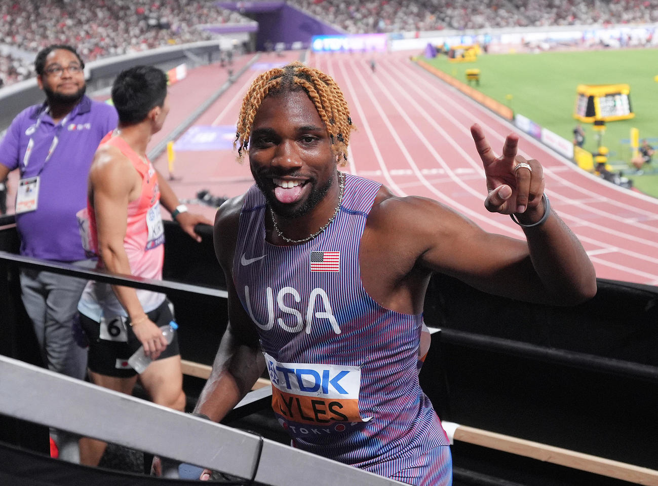 男子100メートル予選を組1着でゴールし笑顔を見せる米国のライルズ。後方は桐生（撮影・足立雅史）