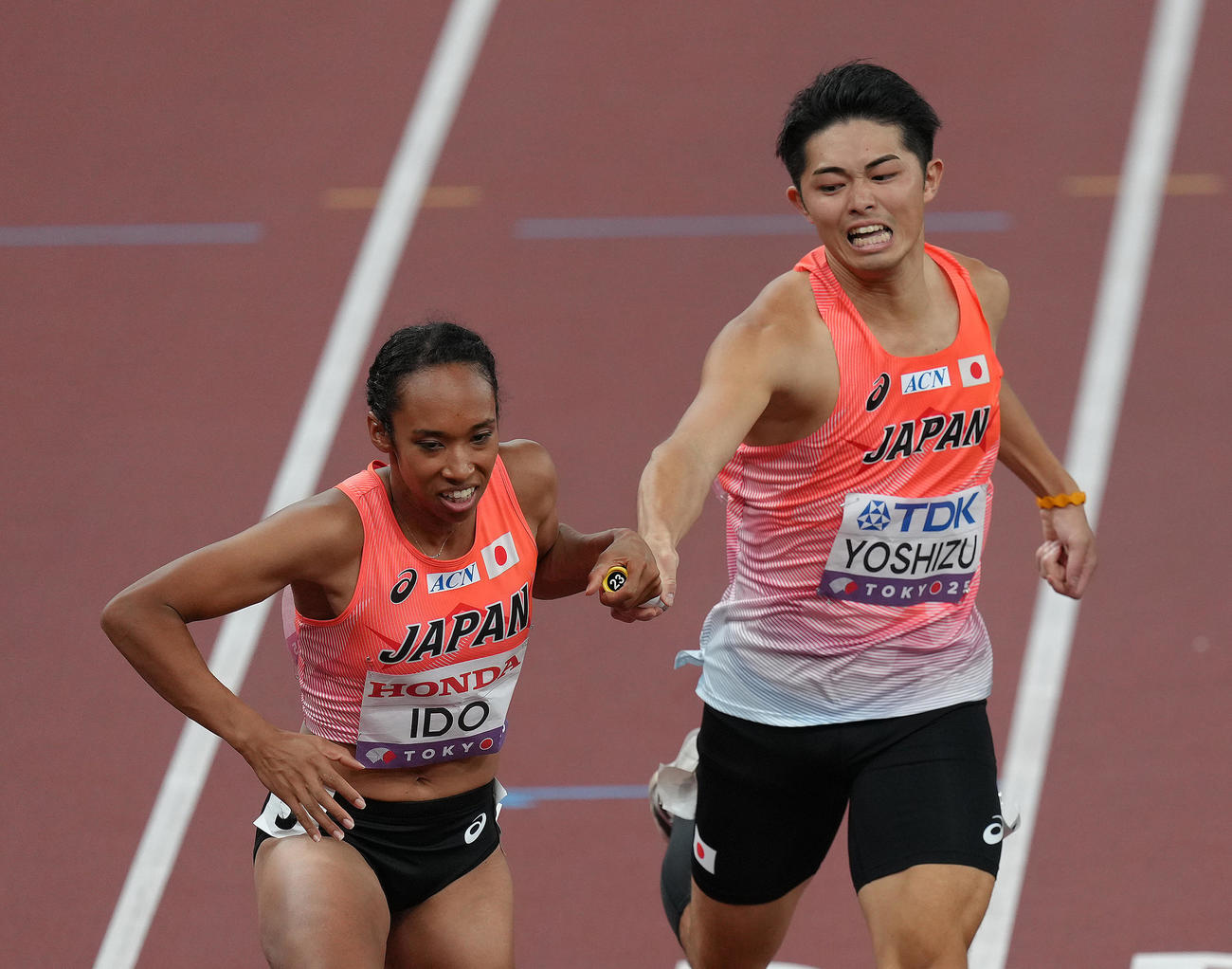 混合1600メートルリレー決勝、1走吉津（右）から2走井戸にバトンが渡る（撮影・足立雅史）