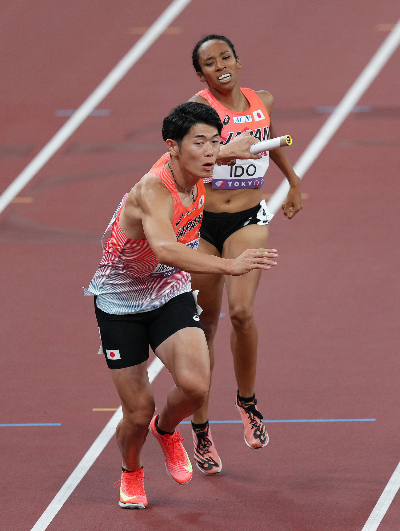 混合1600メートルリレー決勝、2走井戸（右）から3走今泉にバトンが渡る（撮影・足立雅史）