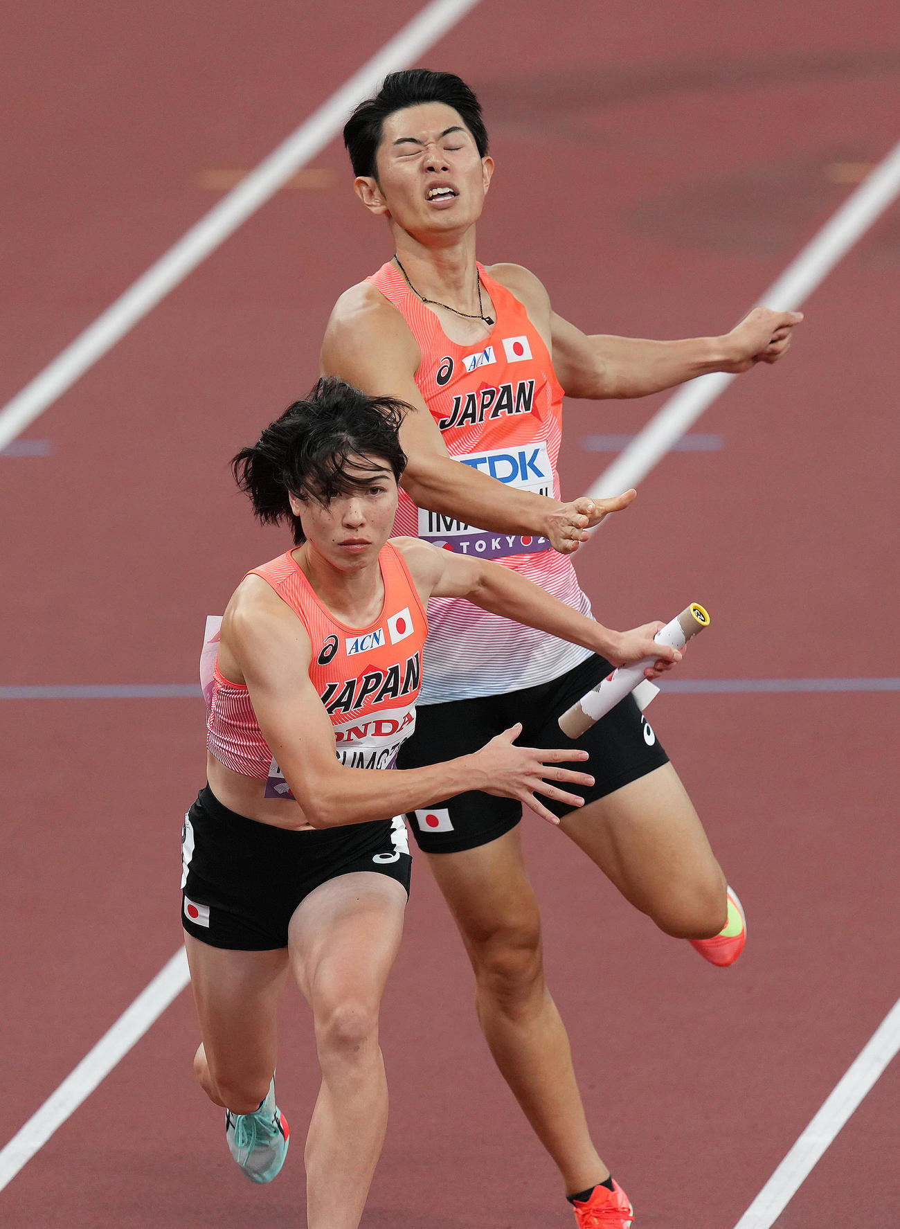 混合1600メートルリレー決勝、3走今泉（右）からアンカーの松本にバトンが渡る（撮影・足立雅史）
