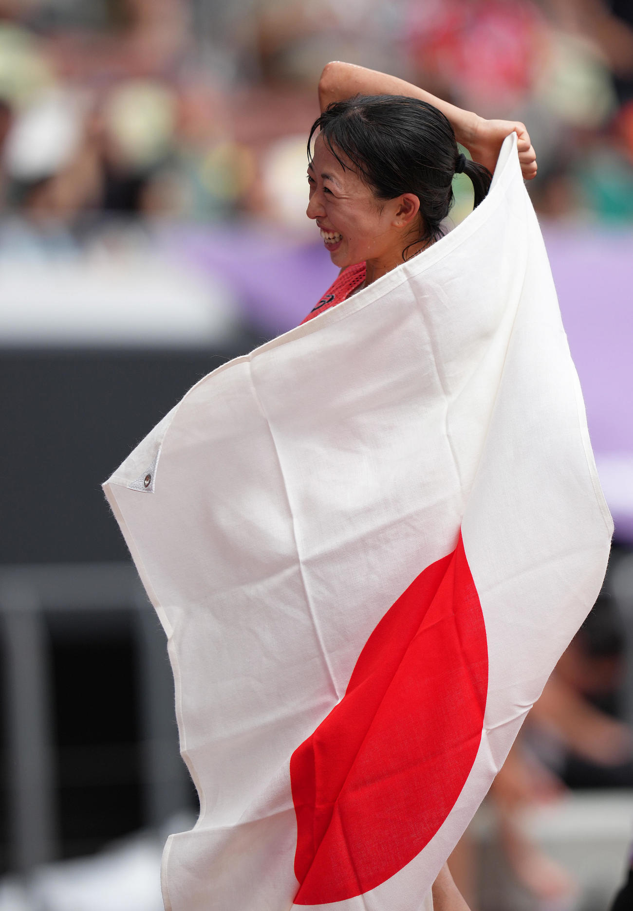 女子マラソンで7位入賞の小林は笑顔で日の丸を身にまとう（撮影・足立雅史）