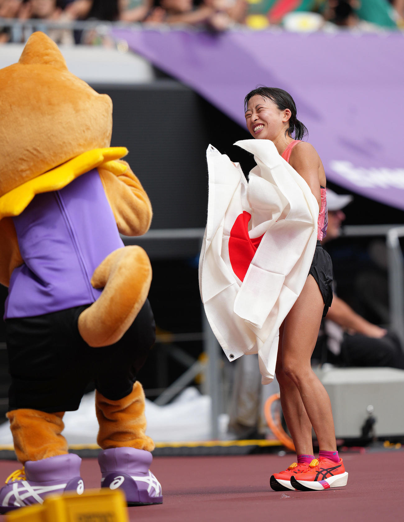 女子マラソンで7位入賞の小林（右）は大会公式マスコット「りくワン」に笑顔（撮影・足立雅史）