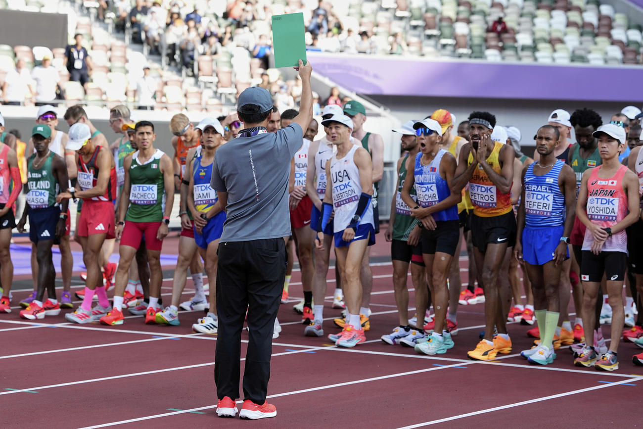 陸上世界選手権の男子マラソンでフライングスタートした選手に審判がグリーンカードを出す（AP）
