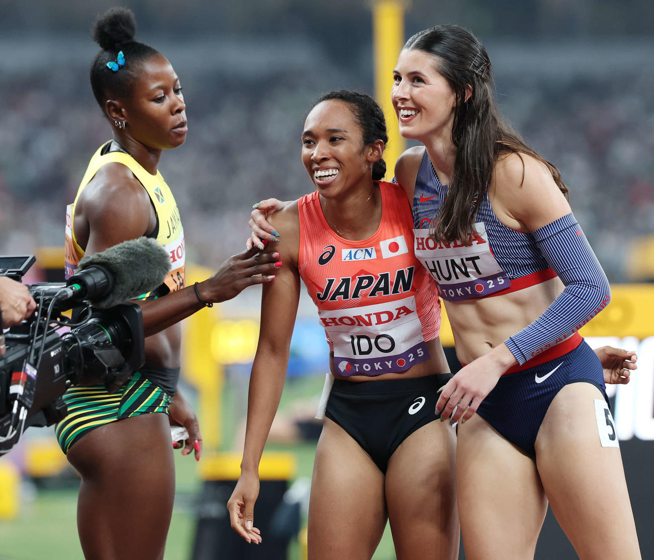 女子200メートル予選　レース後、ジャマイカのジャクソン（左）と米国のハント（右）と笑顔を見せる井戸（撮影・宮地輝）