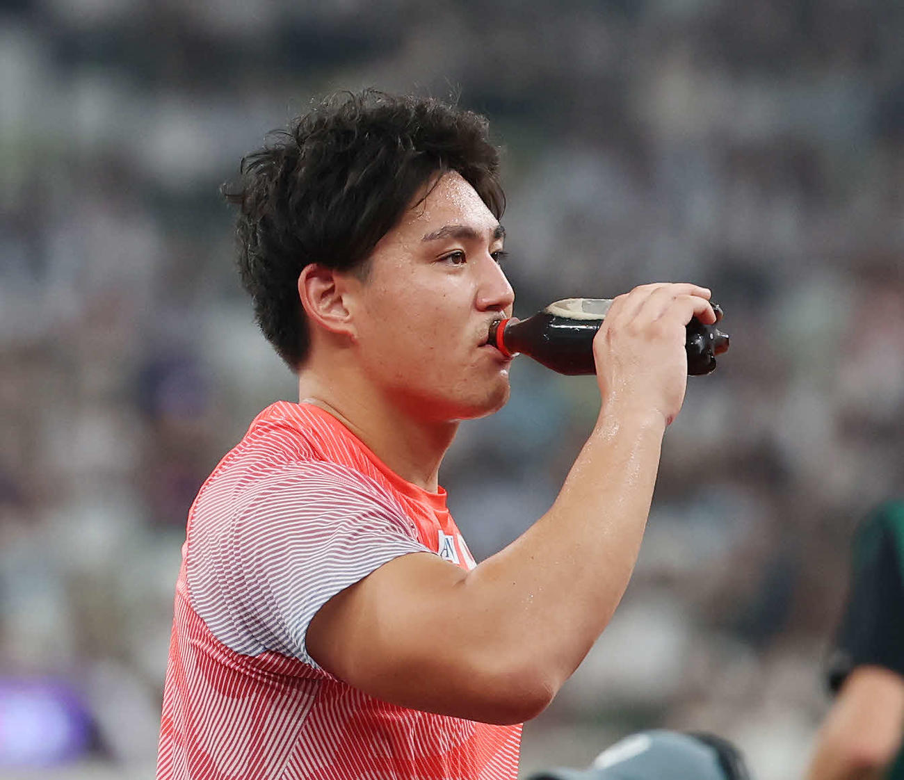 男子やり投げ予選　競技前、コーラを飲む崎山（撮影・宮地輝）