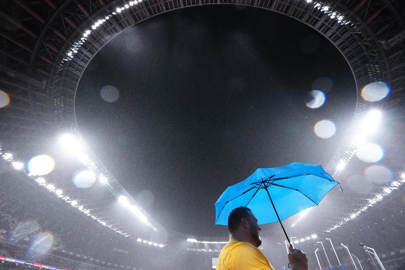 競技中、激しい雨が降り、傘をさし待つ選手たち（撮影・足立雅史）