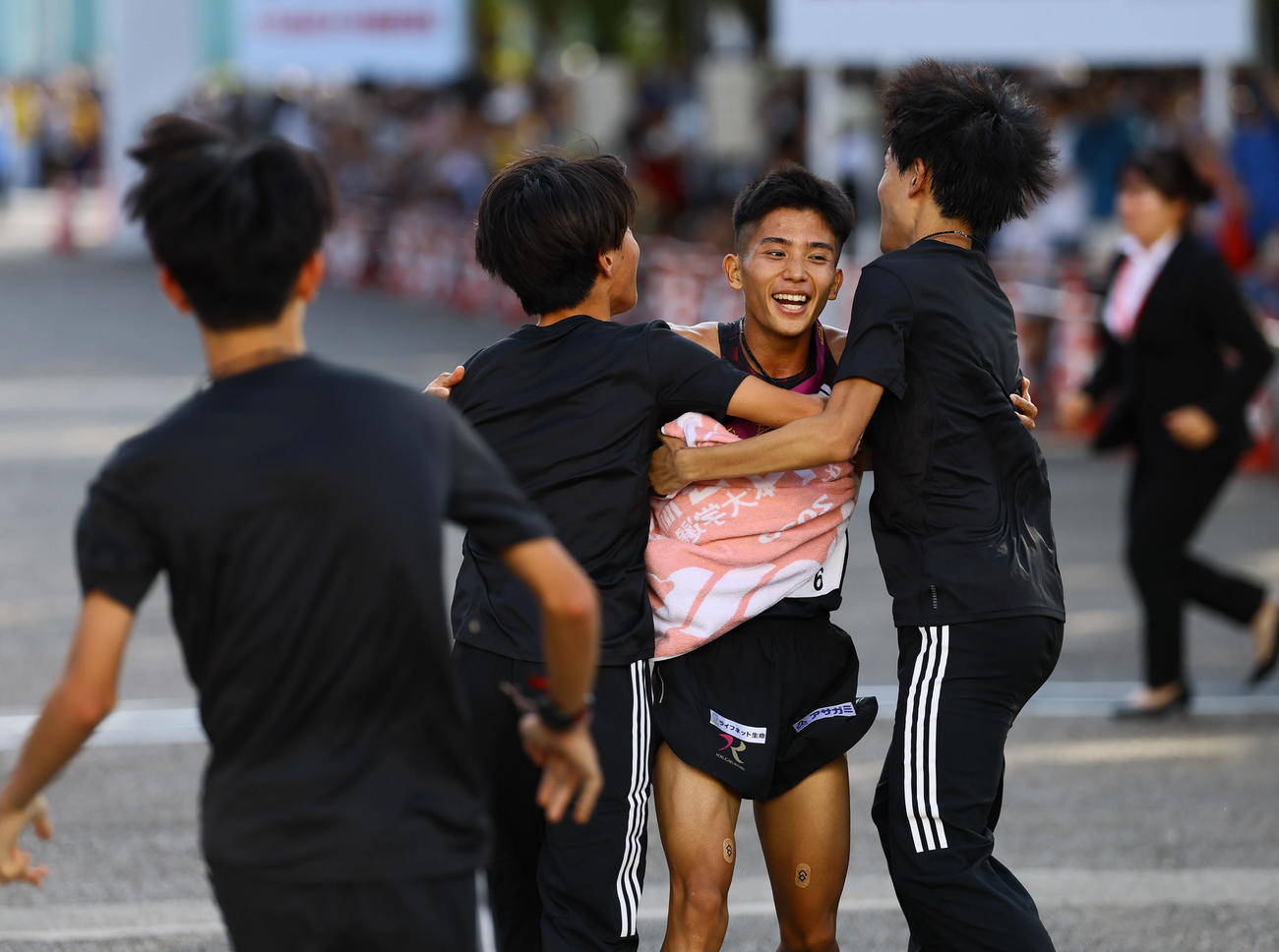 優勝のゴールテープを切り、出迎えられる国学院大アンカーの上原（撮影・藤尾明華）