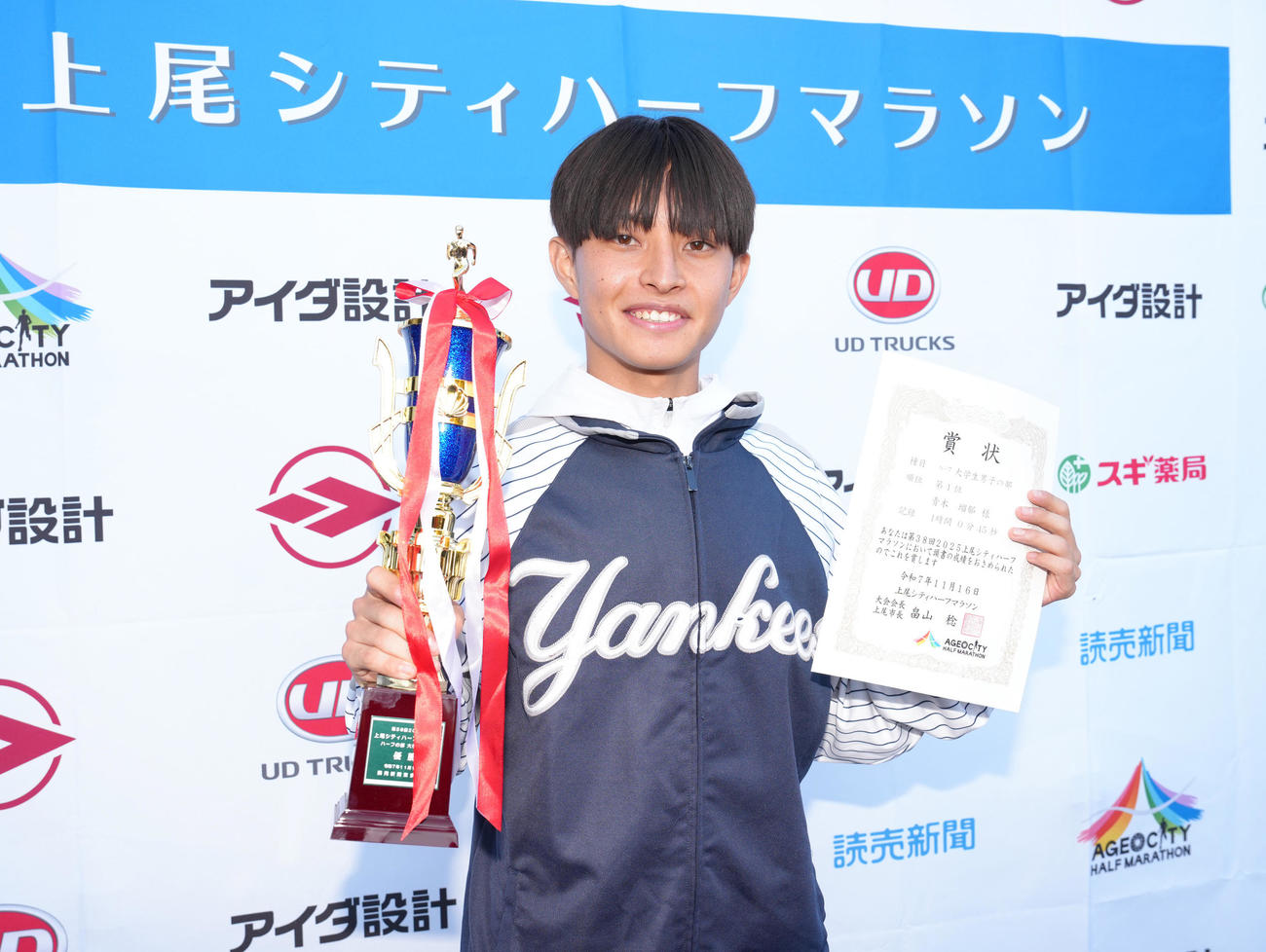 上尾シティハーフマラソンで優勝した国学院大・青木は「ユナイテッド航空NYCハーフマラソン」の出場権を獲得し、記念品のヤンキースのジャンパー姿で笑顔を見せる（撮影・足立雅史）