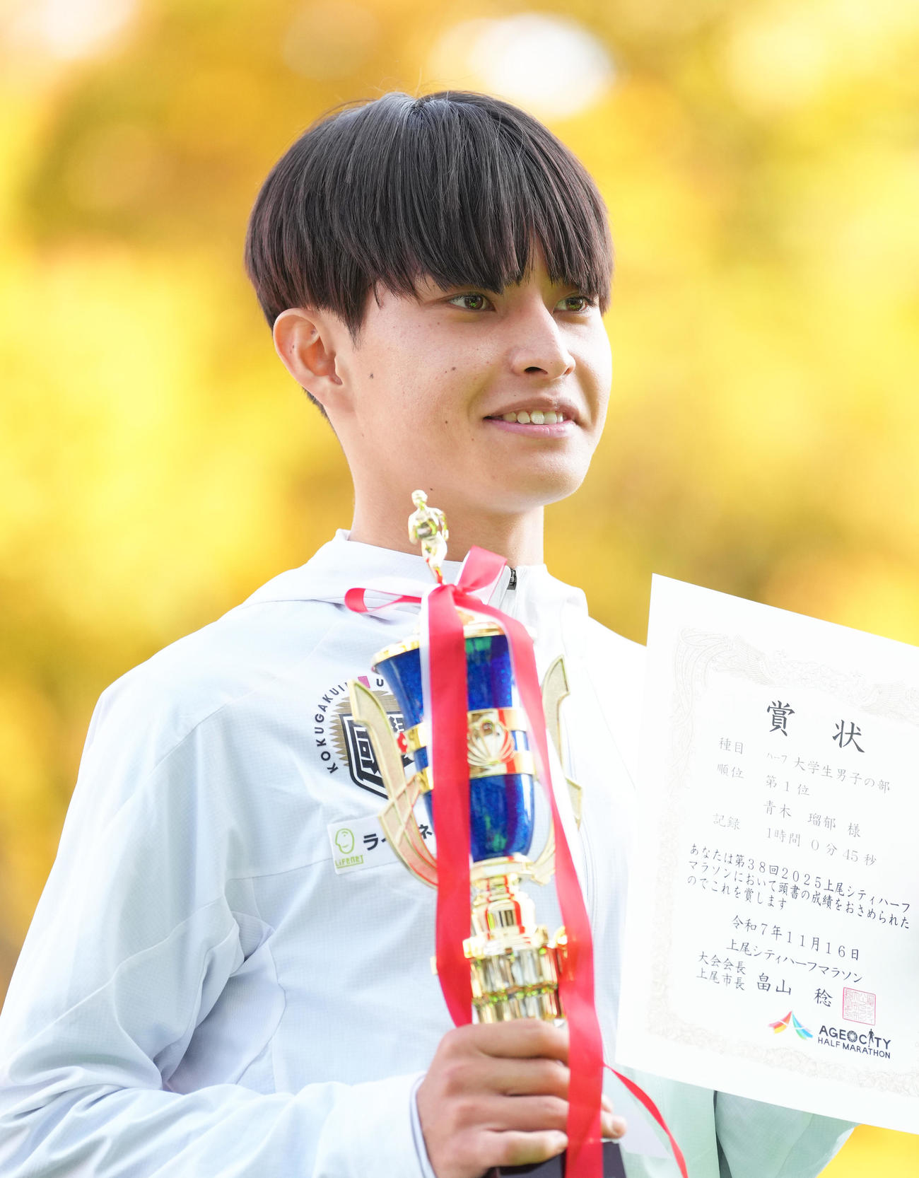 上尾シティハーフマラソンで優勝し、表彰台で笑顔を見せる国学院大・青木（撮影・足立雅史）