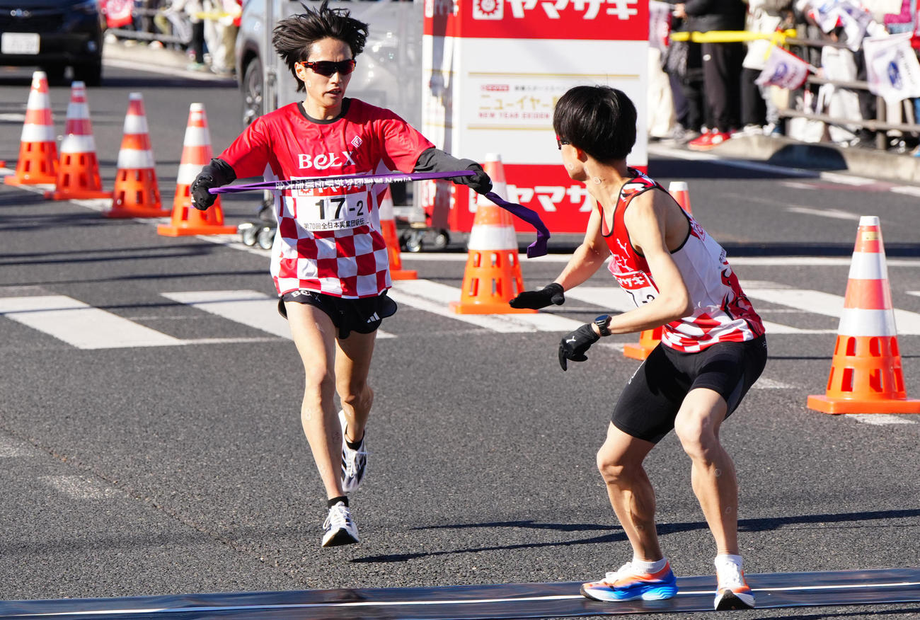 ニューイヤー駅伝の第2中継所でサンベルクス3区越（右）にタスキを渡す2区吉田（撮影・江口和貴）