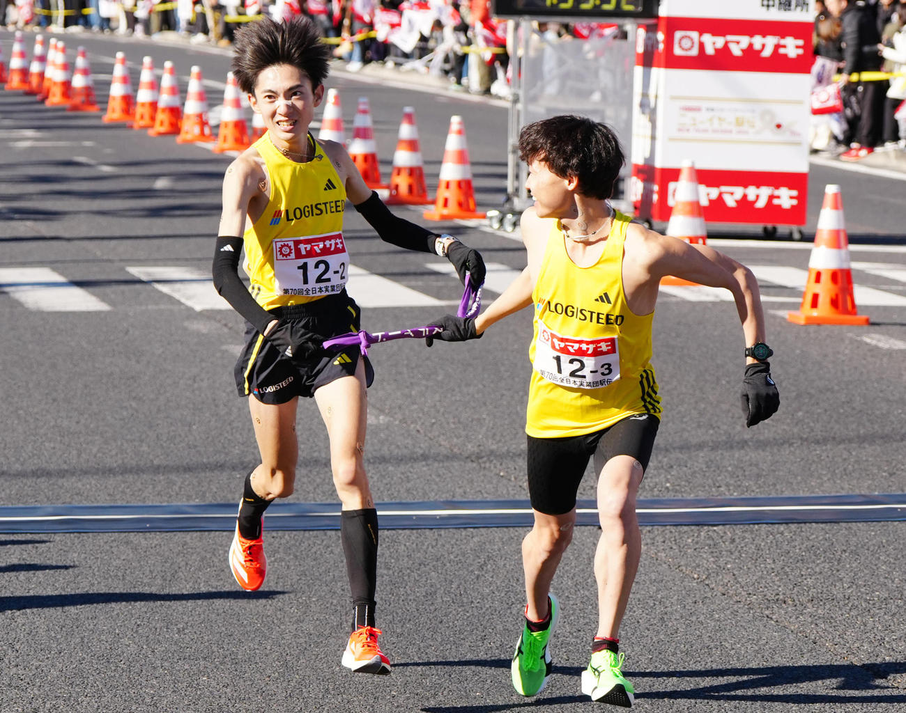 ニューイヤー駅伝の第2中継所でロジスティード3区藤本（右）にタスキを渡す2区平林（撮影・江口和貴）