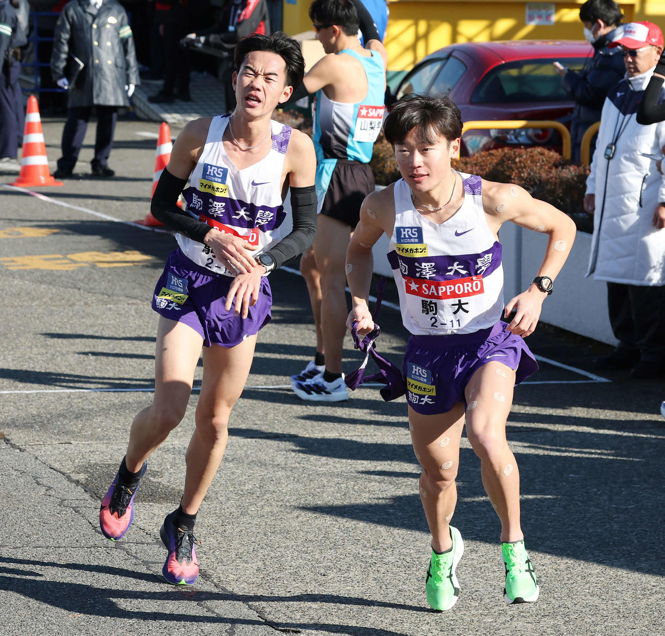 戸塚中継所で駒大3区帰山（右）は2区桑田からタスキを受け駆け出す（撮影・宮地輝）