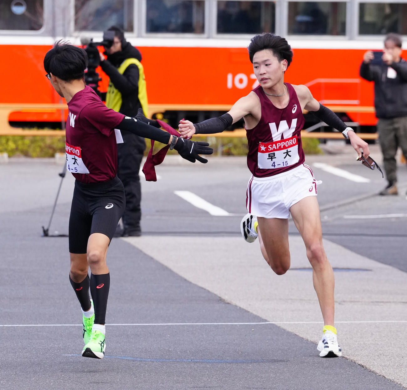 小田原中継所で5区工藤（左）にたすきを渡す早大4区鈴木（撮影・鈴木みどり）