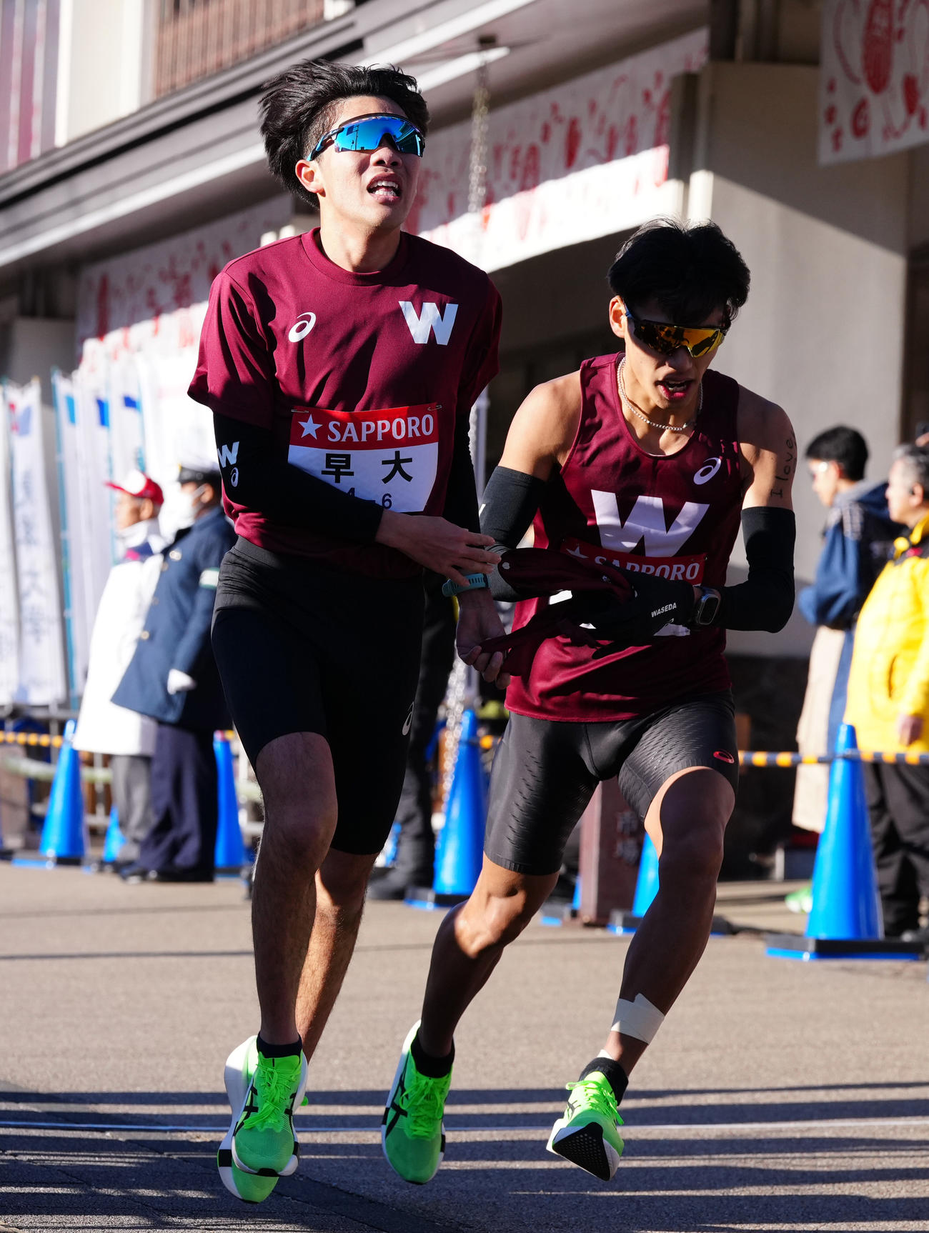 小田原中継所で7区間瀬田（右）にたすきを渡す早大6区山崎（撮影・鈴木みどり）