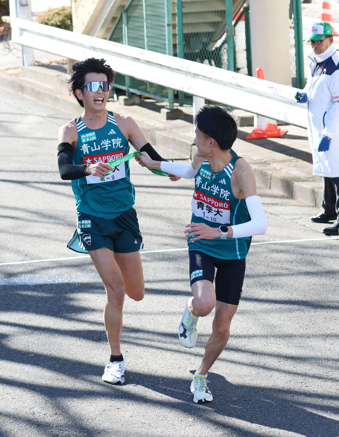 鶴見中継所で10区折田（右）にタスキリレーをする青学大9区佐藤（撮影・増田悦実）