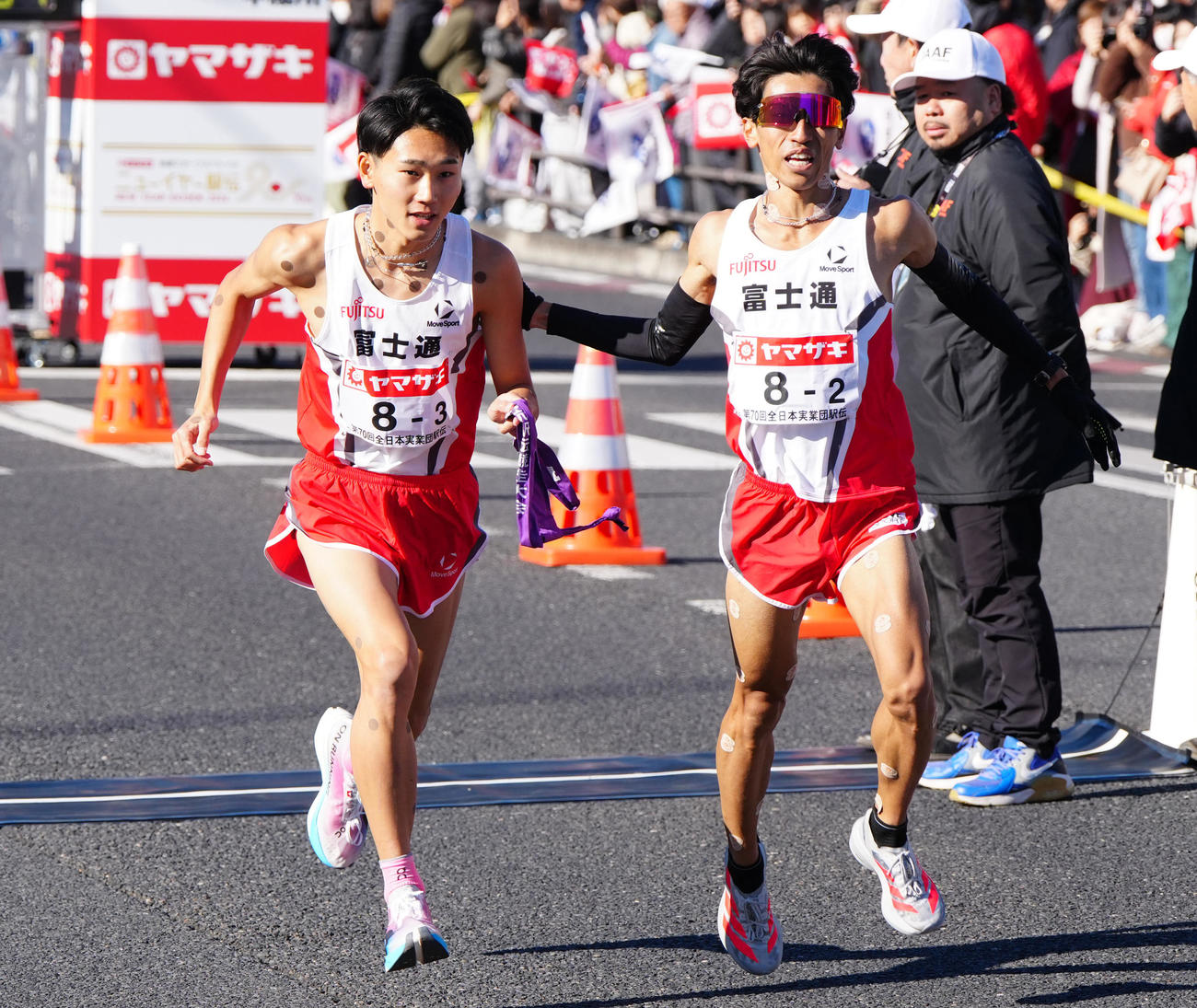 ニューイヤー駅伝の第2中継所で富士通2区浦野（右）からタスキを受け取り駆け出す3区篠原（撮影・江口和貴）