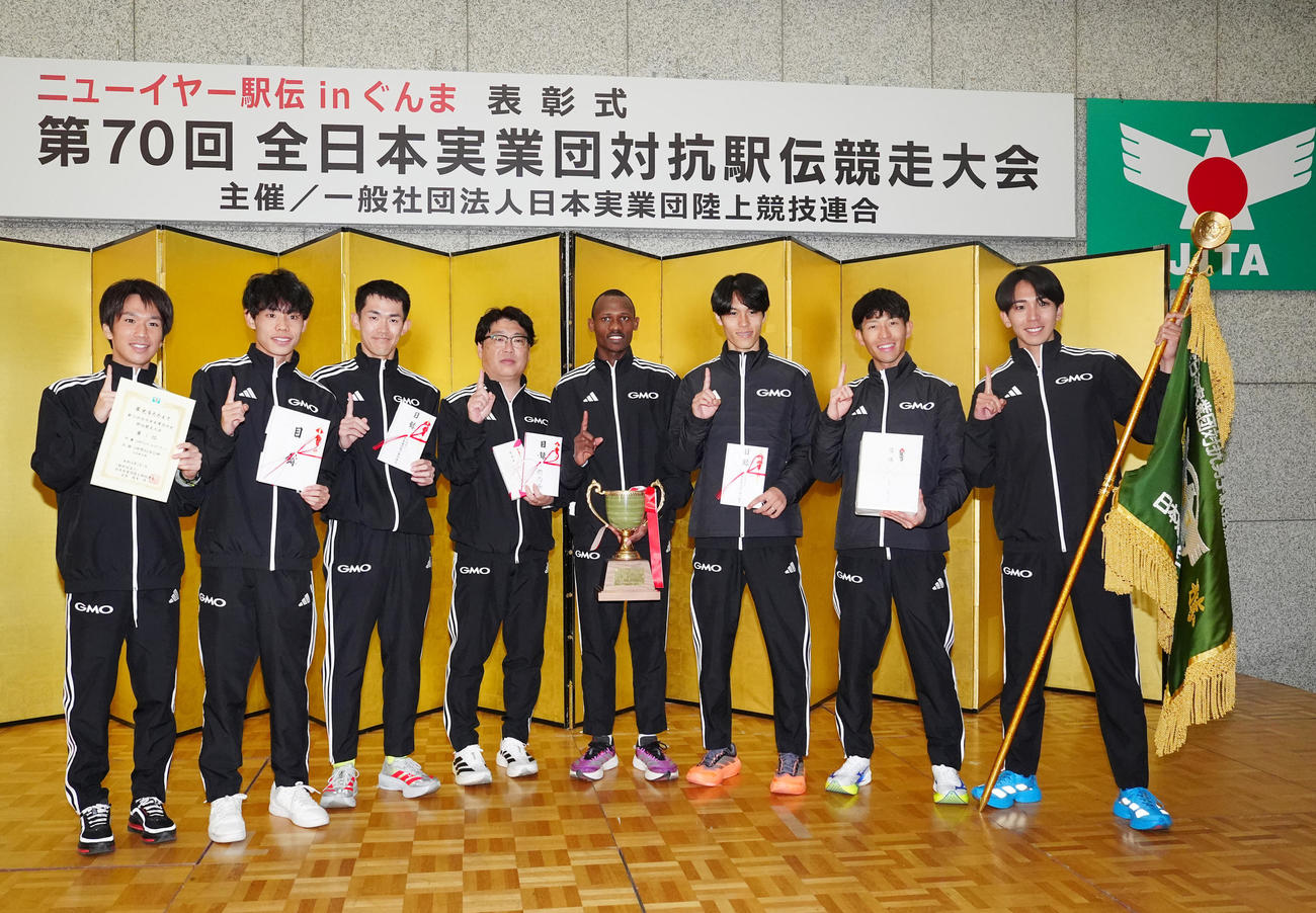 ニューイヤー駅伝で優勝し表彰式で写真に納まるGMOインターネットグループの選手たち。左から1区吉田、2区今江、3区鈴木、伊藤監督、4区テモイ、5区太田、6区嶋津、7区鶴川（撮影・江口和貴）