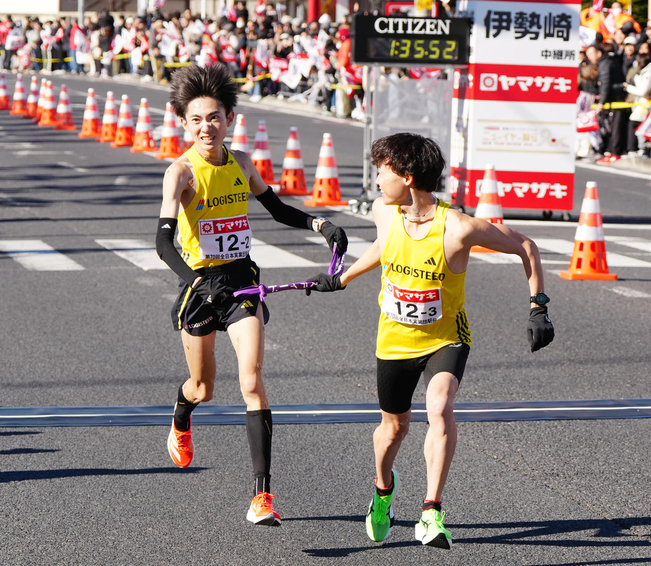 ニューイヤー駅伝の第2中継所でロジスティード3区藤本（右）にタスキを渡す2区平林（撮影・江口和貴）