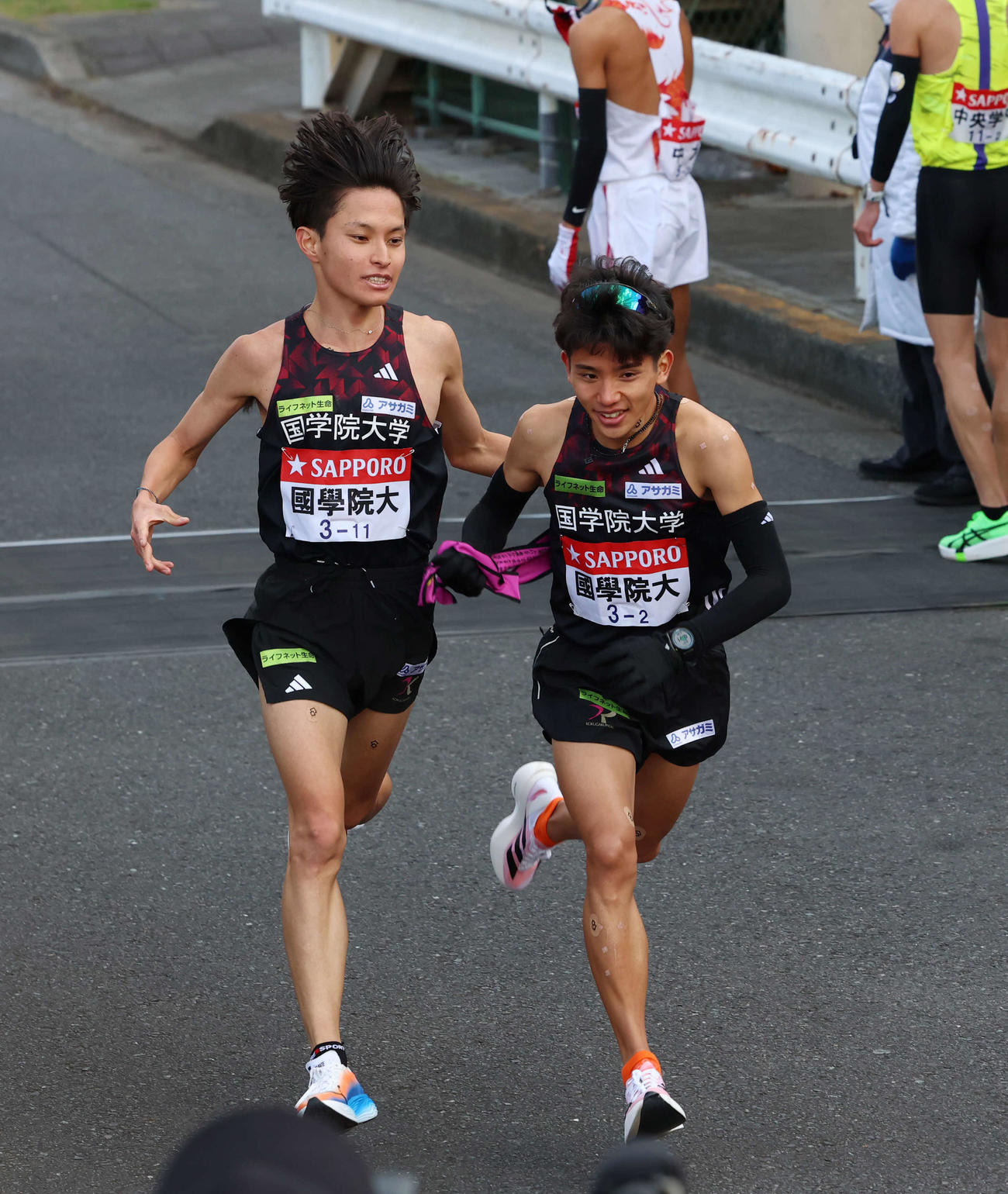 鶴見中継所で国学院大・上原（右）にタスキリレーをする青木（撮影・増田悦実）