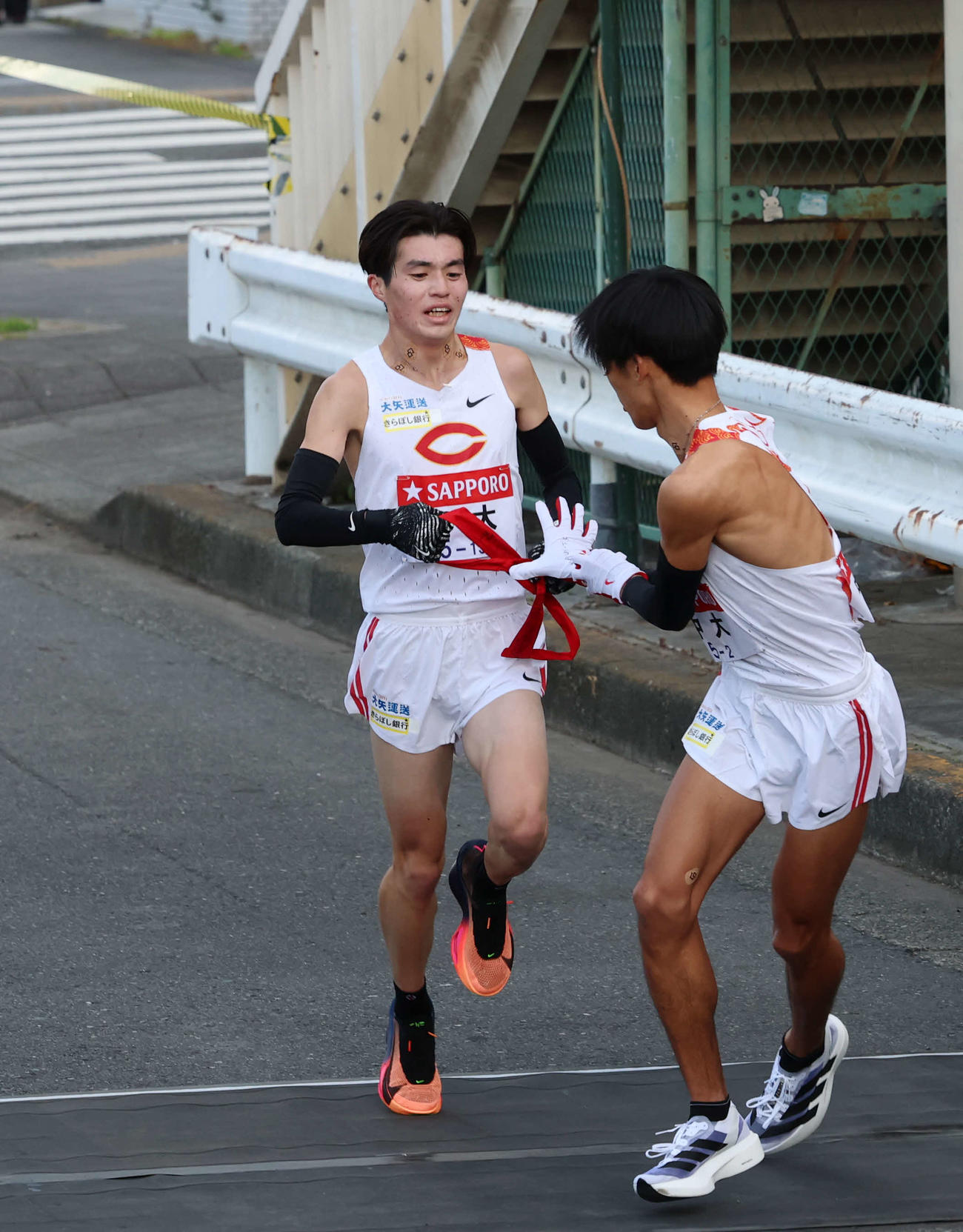 鶴見中継所で中大・溜池（右）にタスキリレーをする藤田（撮影・増田悦実）