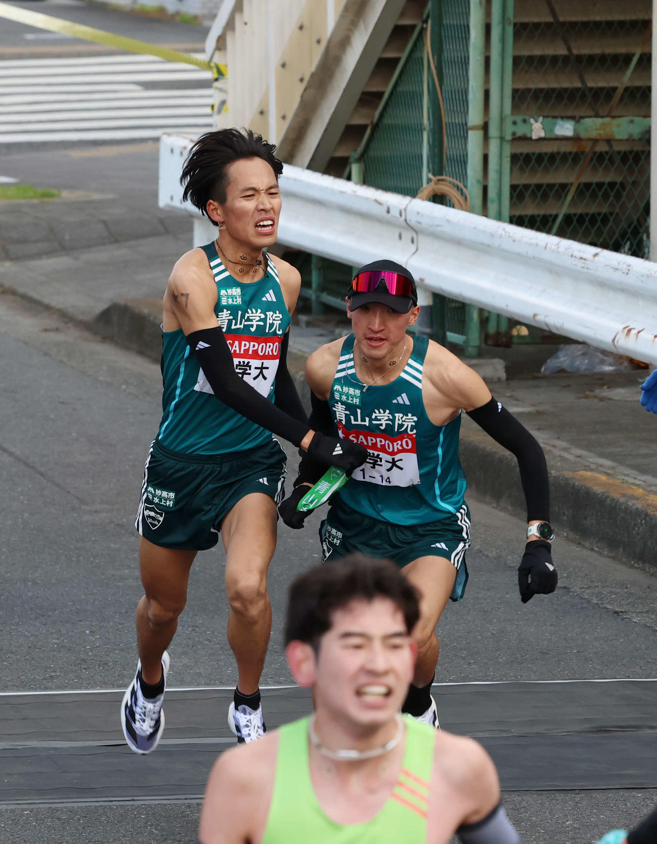 鶴見中継所で青学大・飯田（右）にタスキリレーをする小河原（撮影・増田悦実）