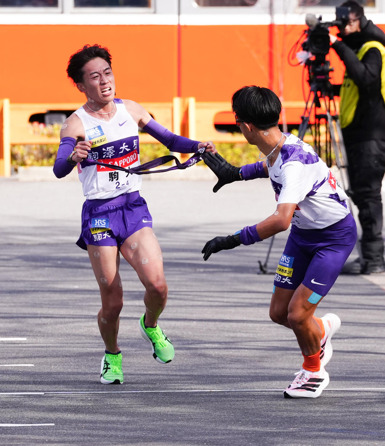 小田原中継所で5区安原（右）にたすきを渡す駒大4区村上（撮影・鈴木みどり）