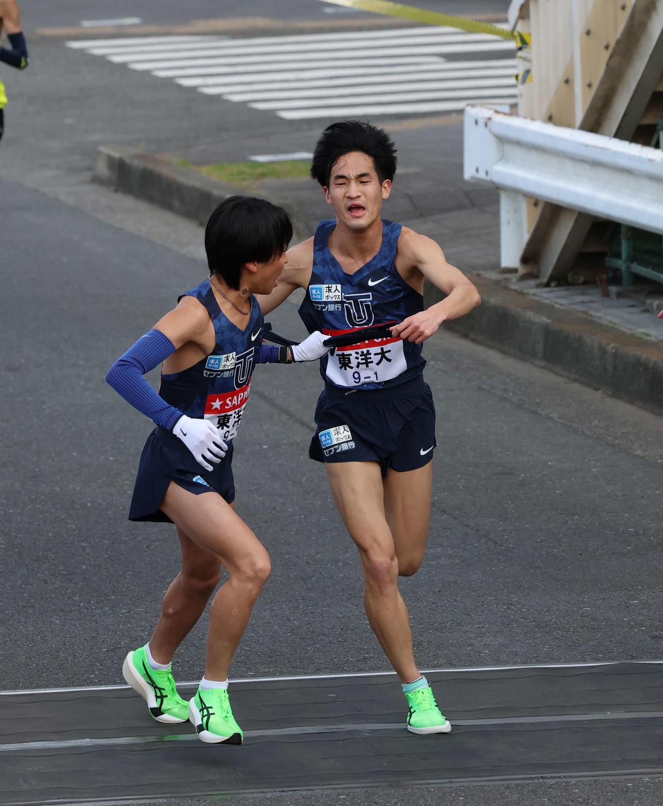 鶴見中継所で東洋大・西村にタスキリレーをする松井（撮影・増田悦実）