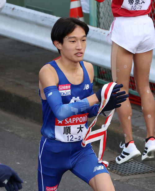 鶴見中継所でタスキを受け取り走り出す順大・吉岡（撮影・増田悦実）