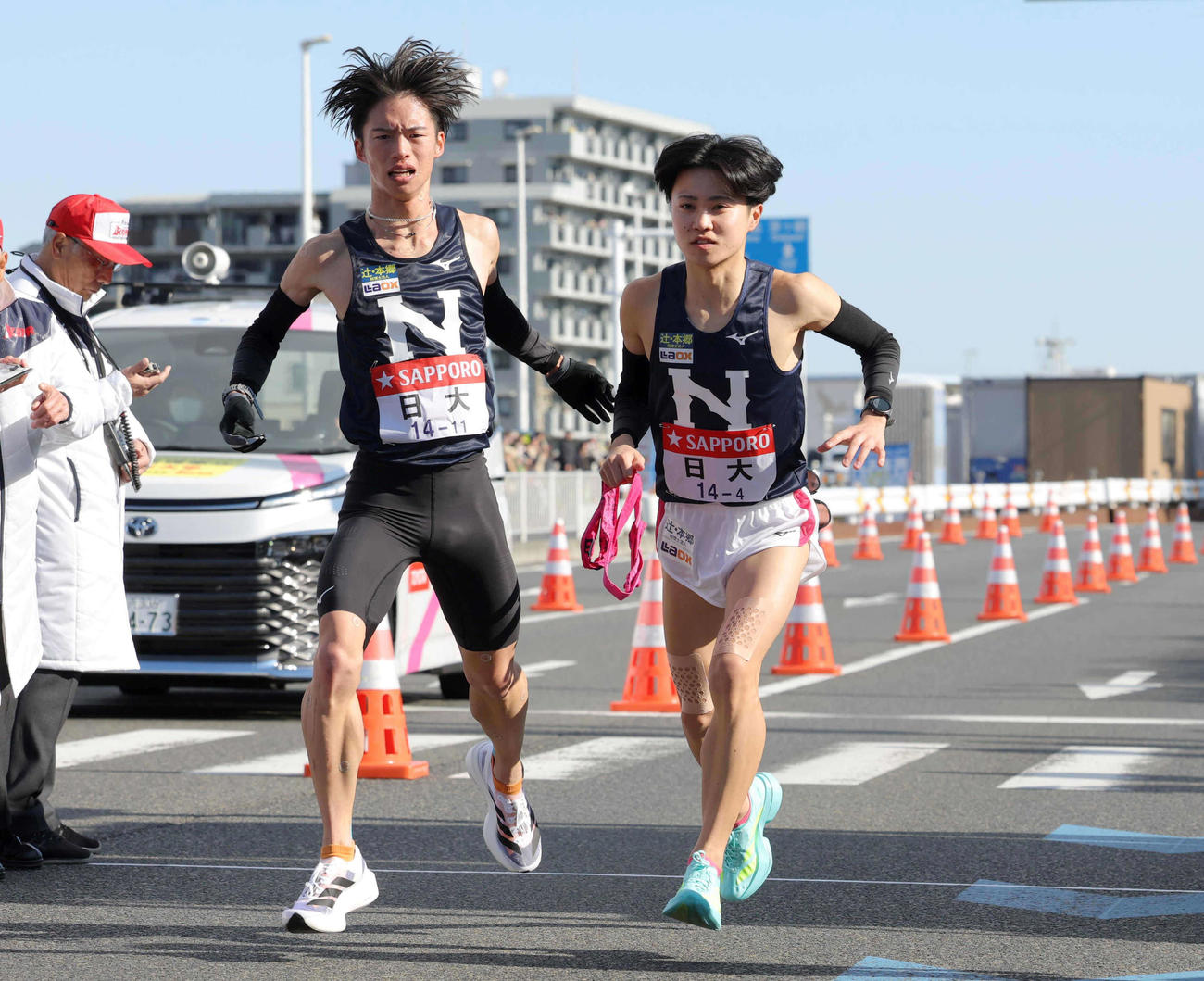 平塚中継所で日大3区冨田（左）から4区片桐へタスキをつなぐ（代表撮影）