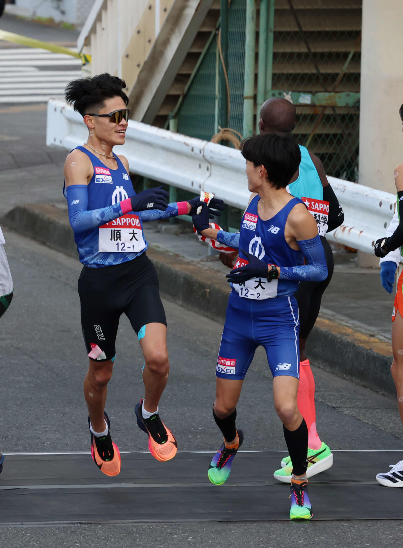 鶴見中継所で順大・吉岡大翔（右）にタスキリレーをする池間（撮影・増田悦実）