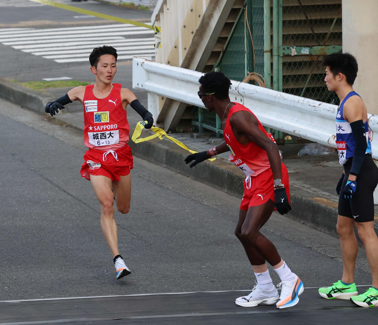 鶴見中継所で城西大・キムタイ（右）にタスキリレーをする柴田（撮影・増田悦実）