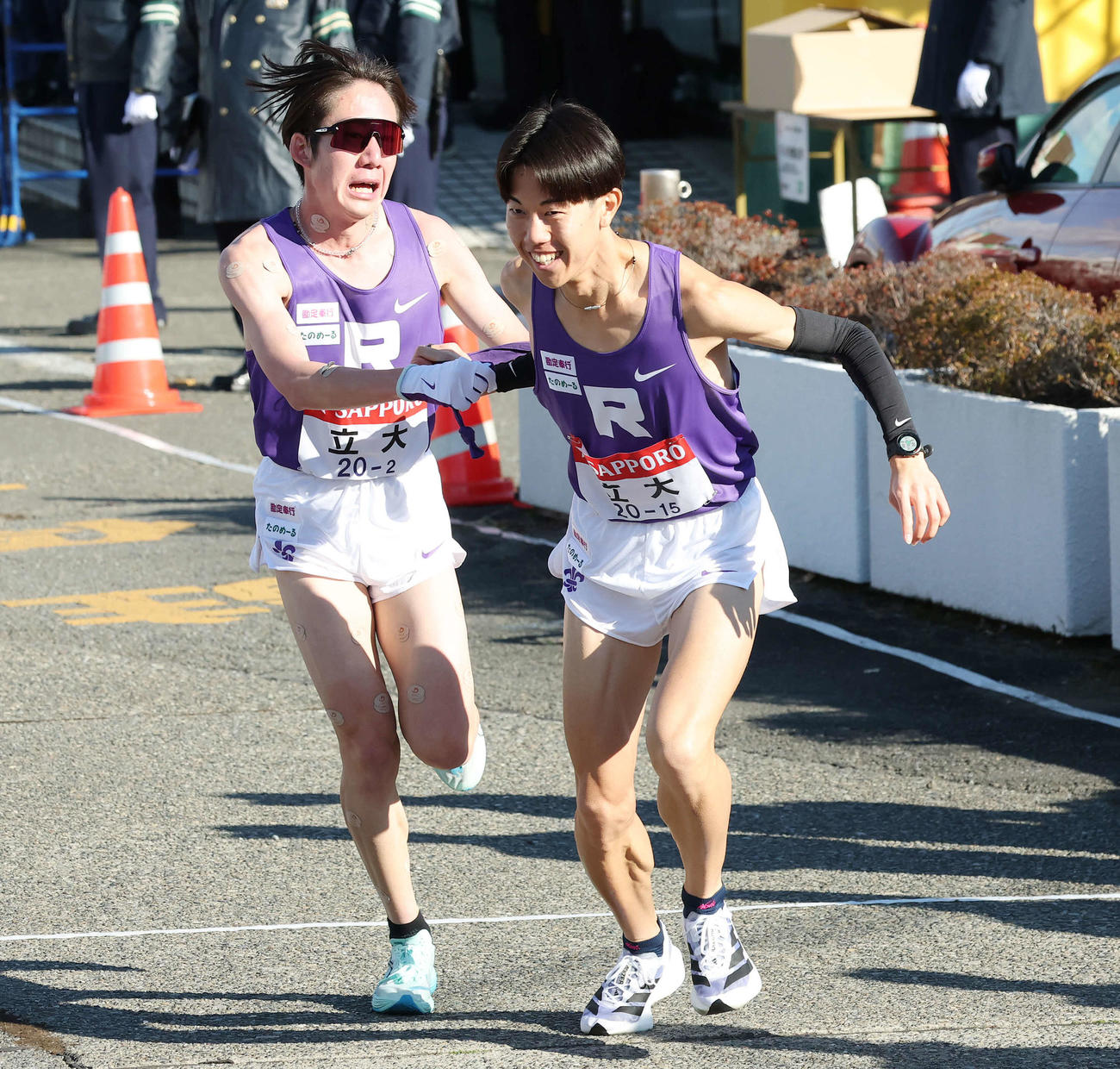 戸塚中継所で立大2区馬場（左）からタスキを受け駆け出す3区原田（撮影・宮地輝）