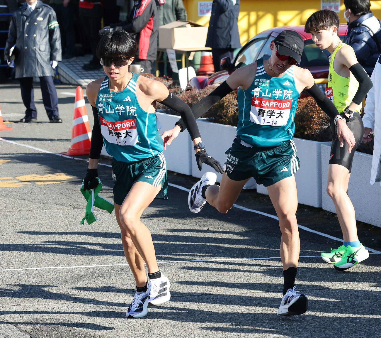 戸塚中継所で青学大3区宇田川（左）は2区飯田からタスキを受け駆け出す（撮影・宮地輝）