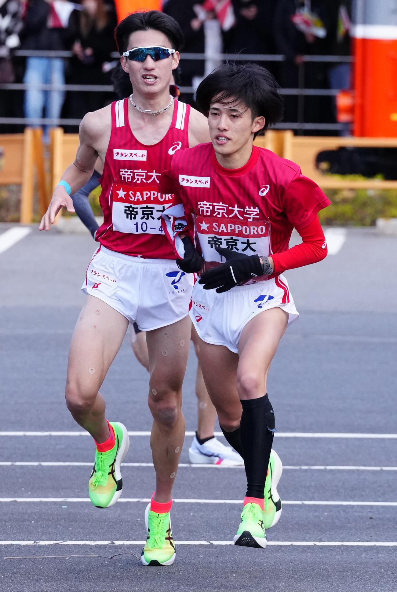 小田原中継所で5区浅川（右）にたすきを渡す帝京大4区谷口（撮影・鈴木みどり）