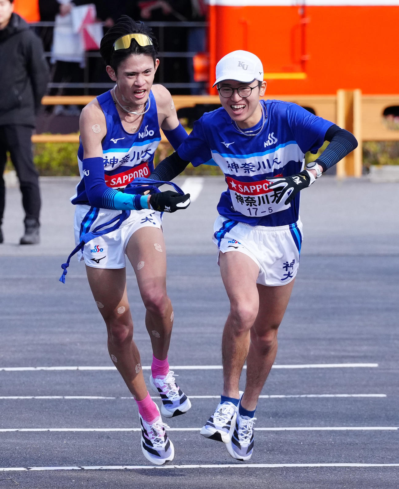 小田原中継所で5区三原（右）にたすきを渡す神奈川大4区平川（撮影・鈴木みどり）