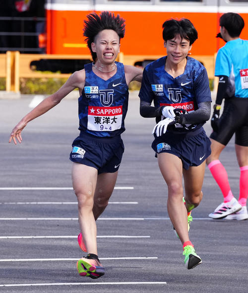 小田原中継所で5区宮崎（右）にたすきを渡す東洋大4区緒方（撮影・鈴木みどり）