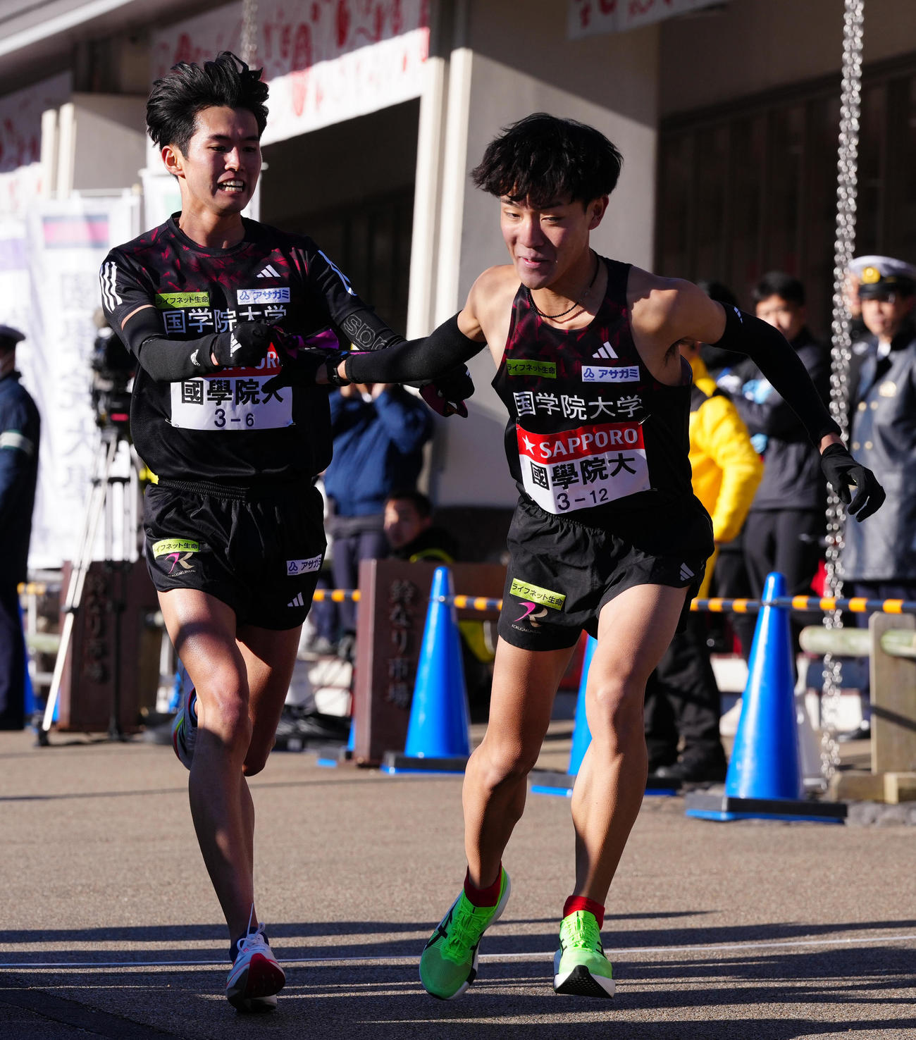 小田原中継所で7区高山（右）にたすきを渡す国学院大6区後村（撮影・鈴木みどり）