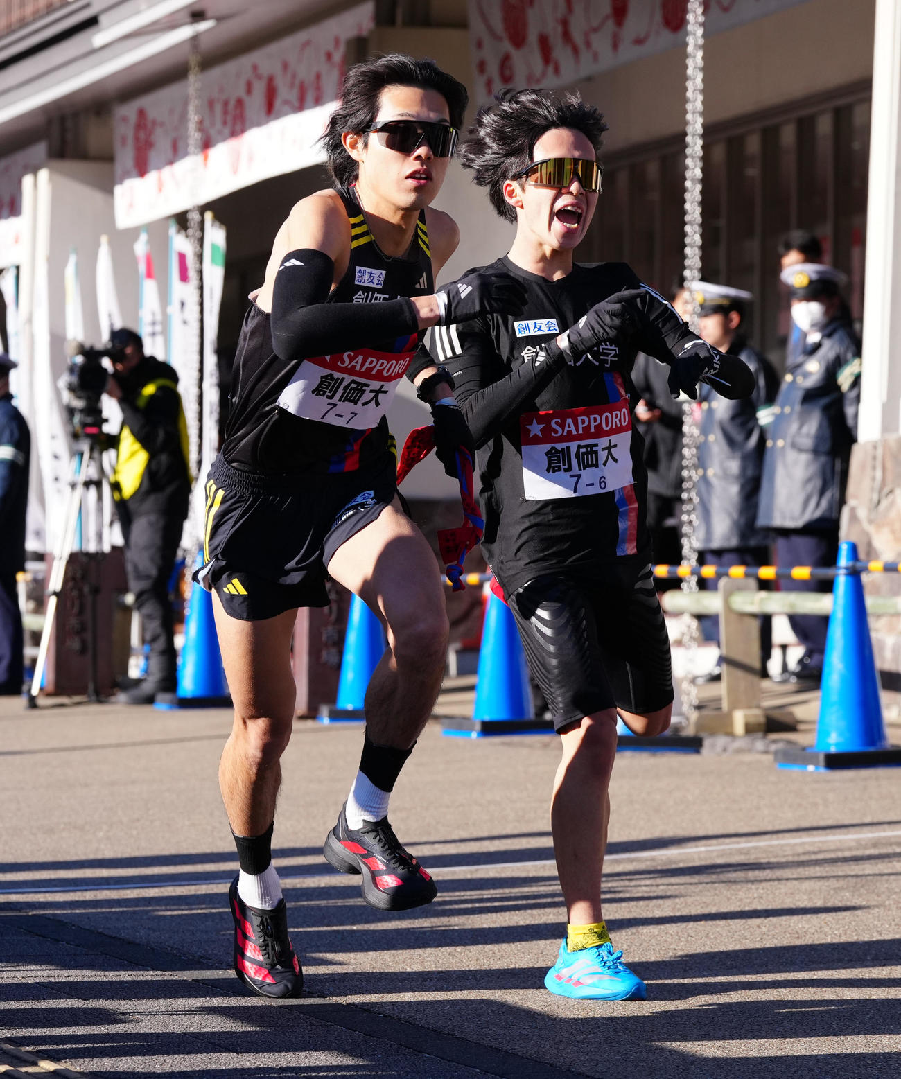 小田原中継所で7区石丸（左）にたすきを渡す創価大6区小池（撮影・鈴木みどり）