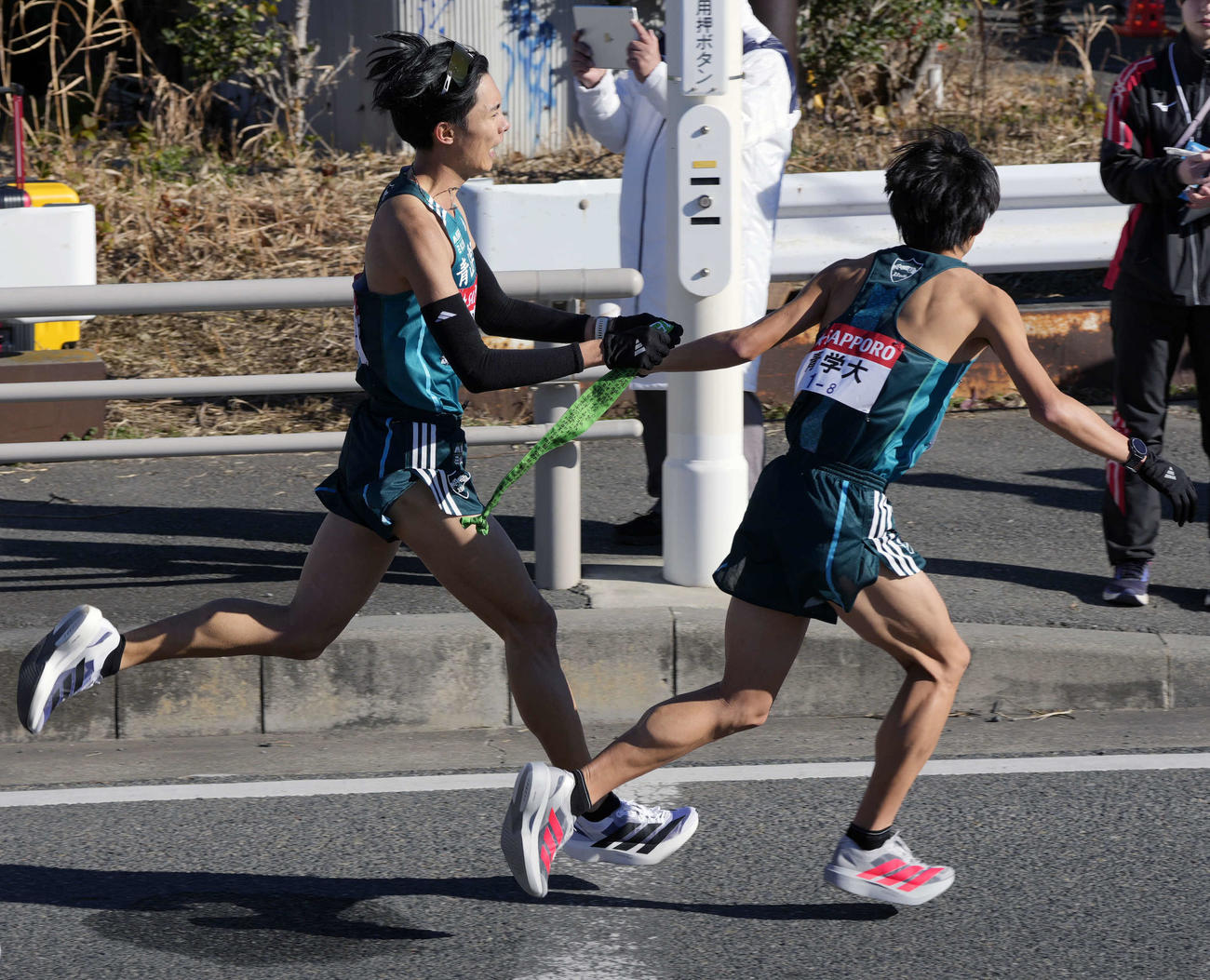 平塚中継所に向かう青学大7区佐藤愛（左）は塩出にタスキをつなぐ（撮影・小島史椰）