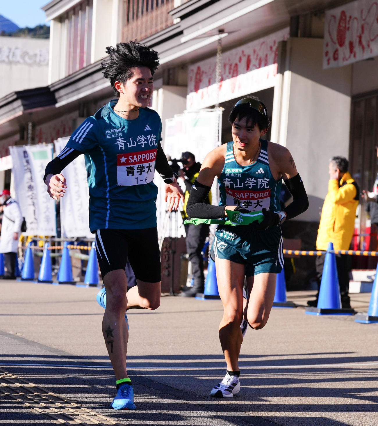 小田原中継所で7区佐藤（右）にたすきを渡す青学大6区石川（撮影・鈴木みどり）