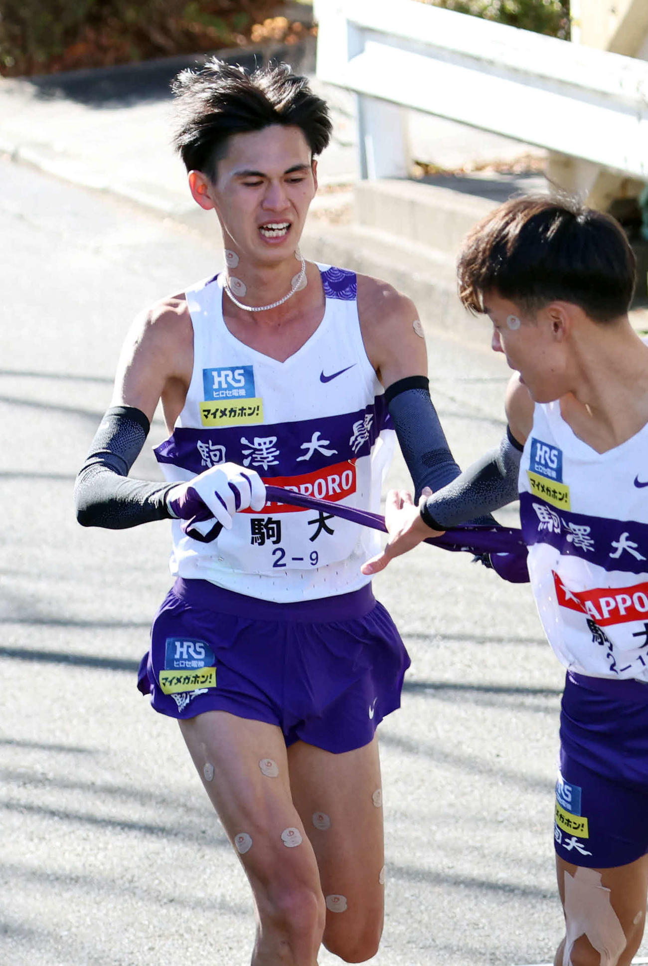鶴見中継所で10区佐藤（右）にタスキリレーをする駒大9区菅谷（撮影・増田悦実）