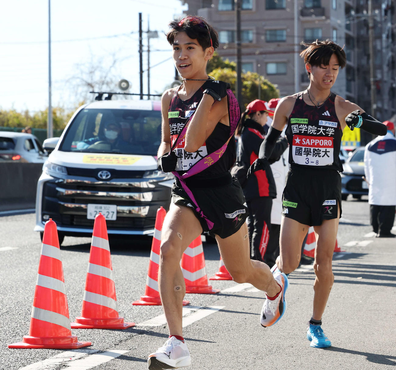 戸塚中継所で国学院大9区野田（左）は8区飯国からタスキを受け駆け出す（撮影・宮地輝）